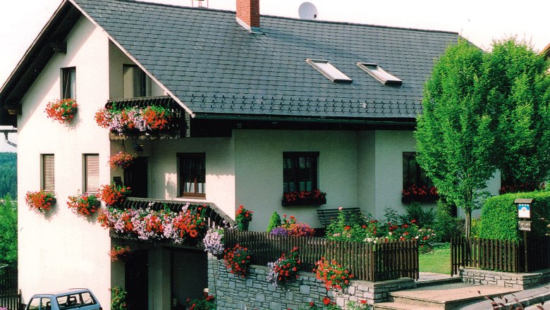 Ferienwohnung Pfeiffer-Vogl, © Ferienwohnung Pfeiffer-Vogl Ein zweistöckiges Haus mit Blumen geschmückten Balkonen und einem kleinen Garten.