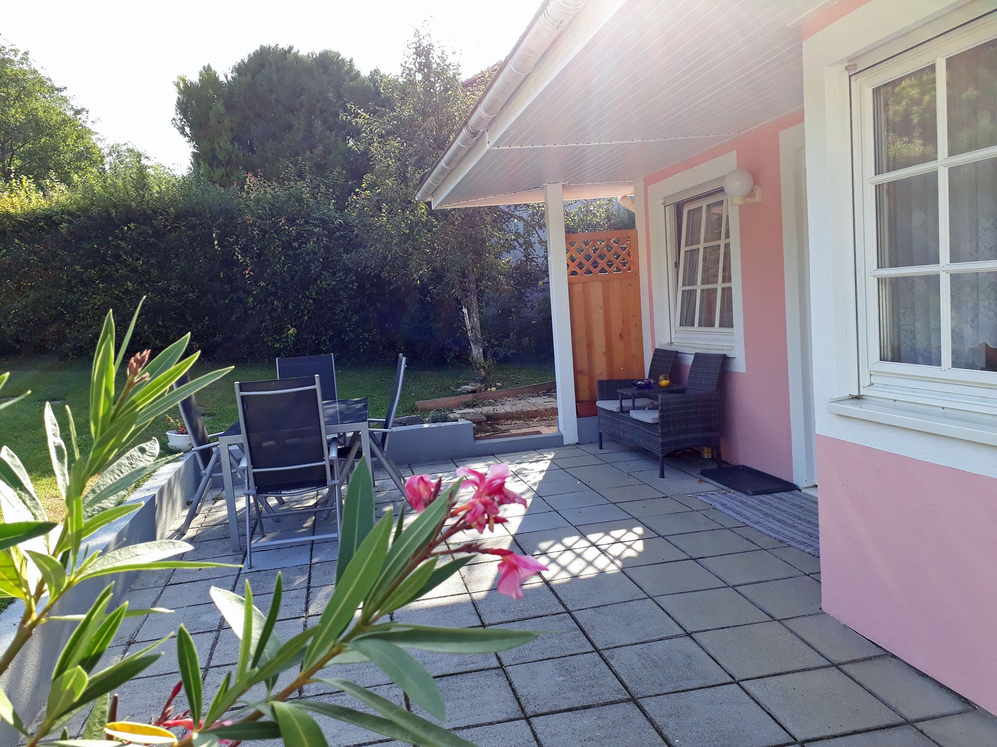 Terrasse mit Gartenmöbeln und rosa Hausfassade.