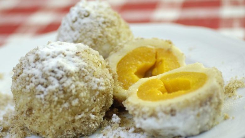 Drei Marillenknödel auf einem Teller, einer davon aufgeschnitten