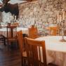 Rustikales Restaurant mit Steinwand, Holzmöbeln und Kerzenleuchtern.