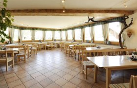 Innenansicht eines Heurigenlokals mit Holzm&ouml;beln und gro&szlig;en Fenstern.