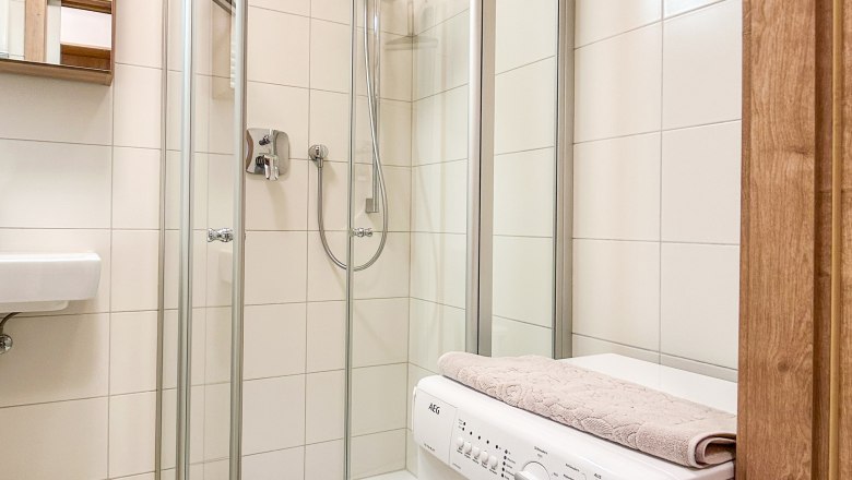 Modernes Badezimmer mit Dusche und Waschmaschine.