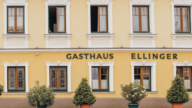 Fassade eines gelben Gasthauses mit der Aufschrift 'Gasthaus Ellinger'.