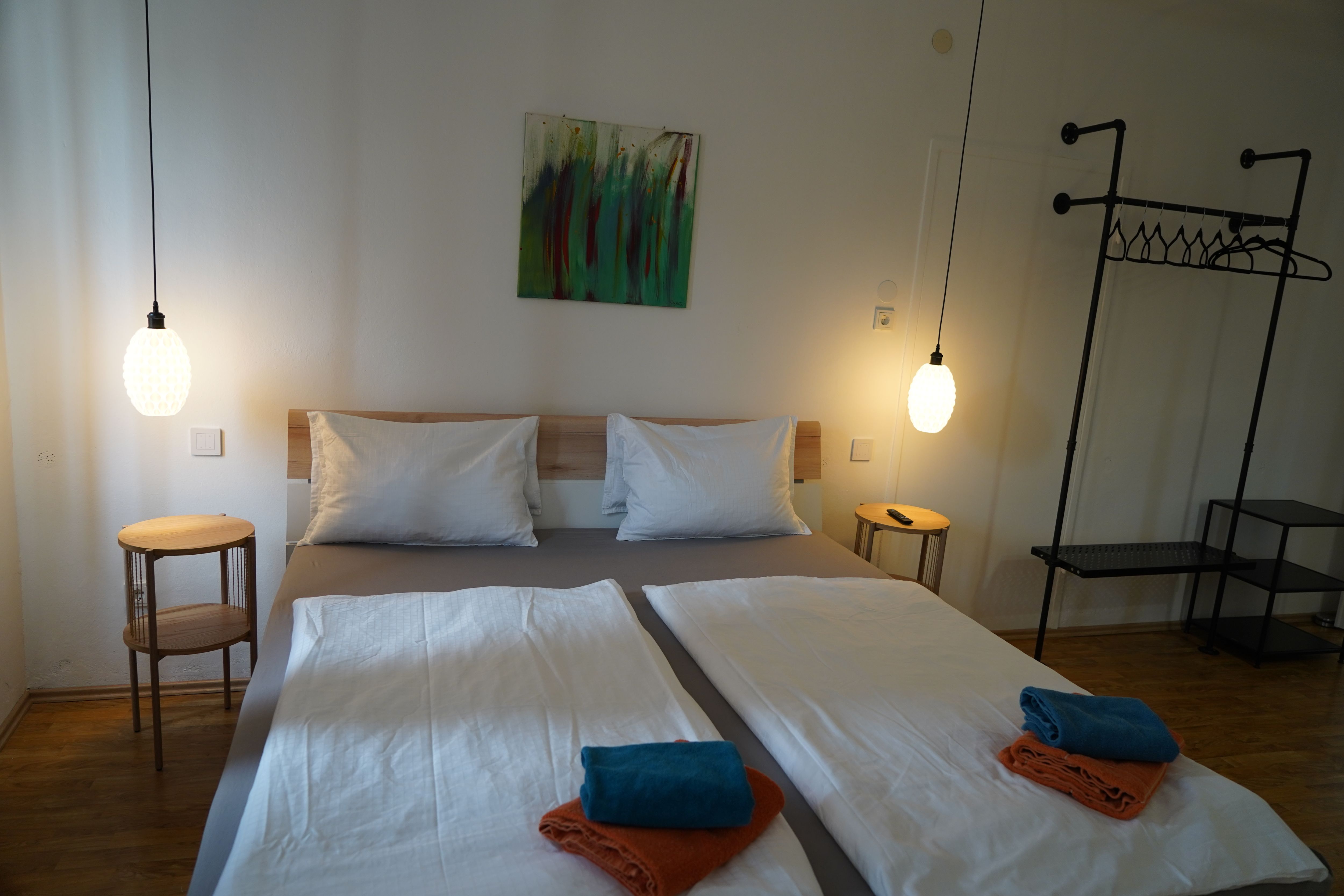 Modernes Schlafzimmer mit Doppelbett, zwei Nachttischen, Hängelampen und Handtüchern auf dem Bett.