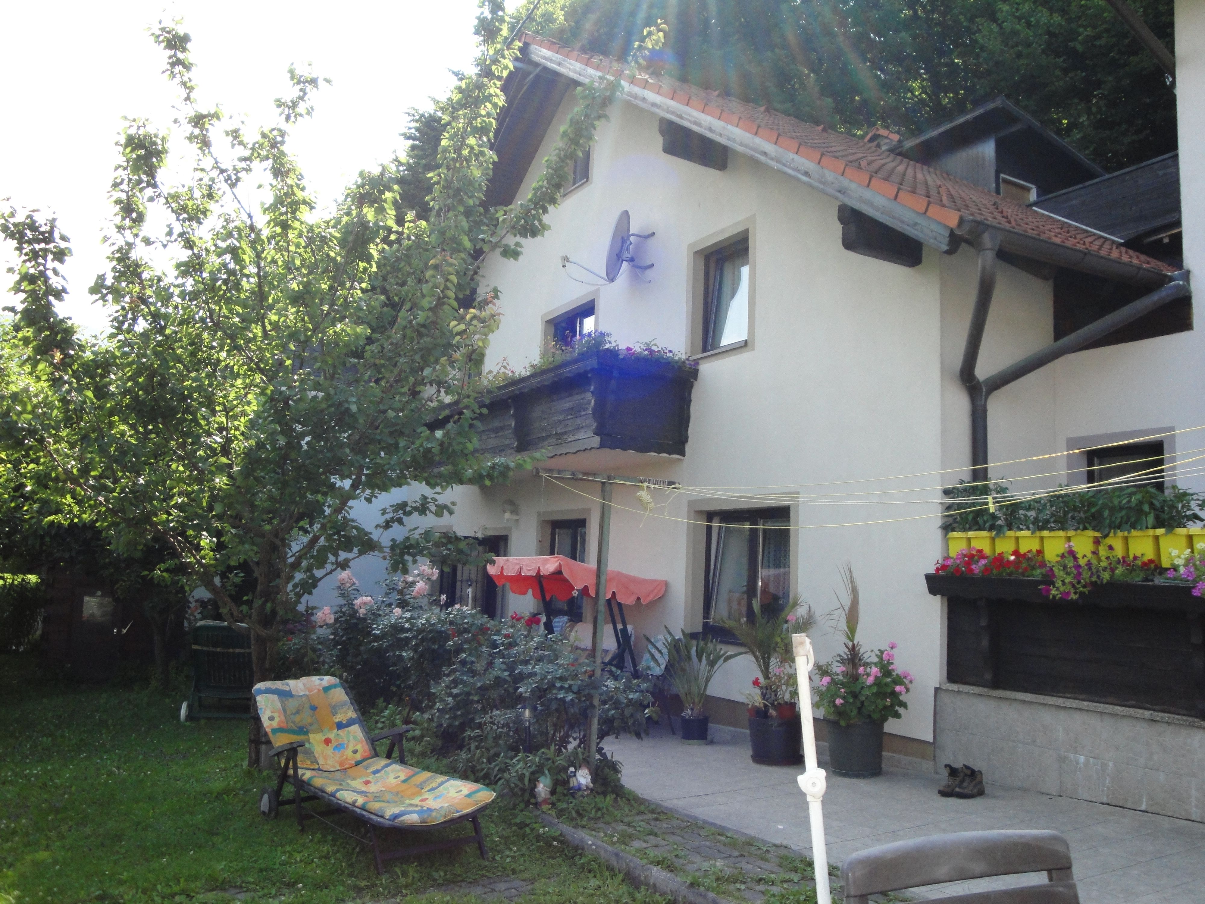 Ein Haus mit Garten, Liegestuhl und Blumen auf der Terrasse.