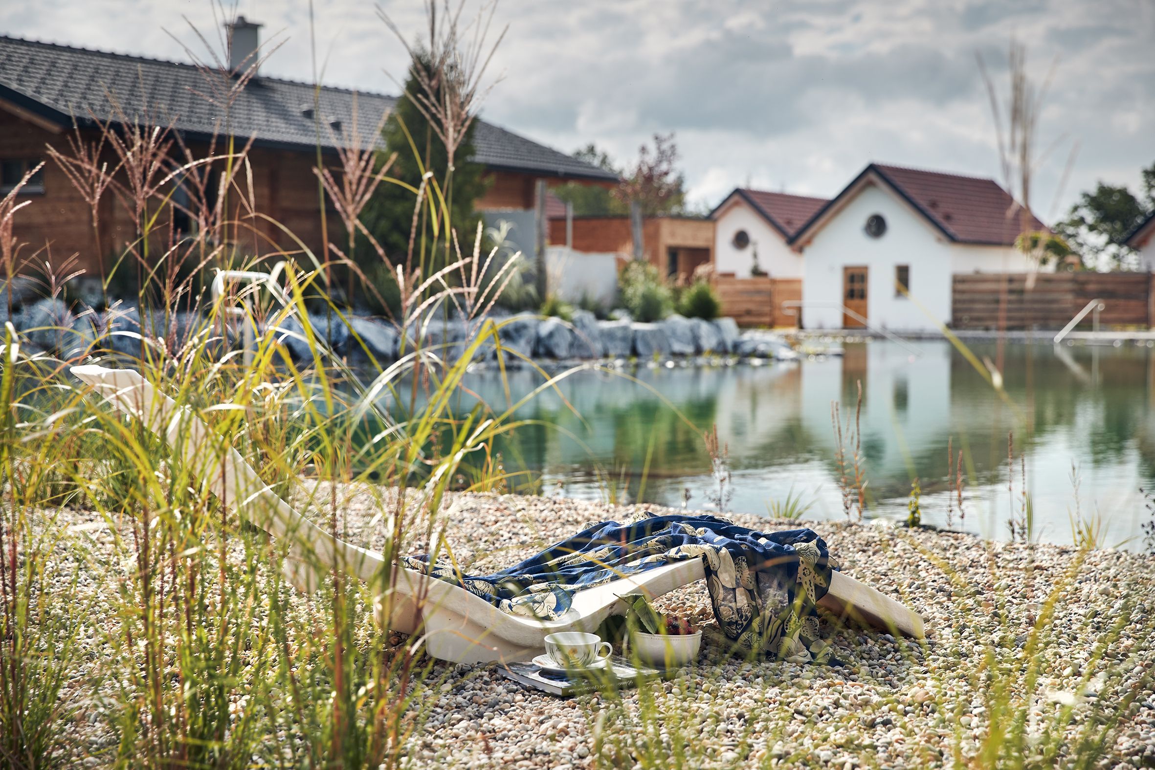 Luftaufnahme von Chalets am Gartensee mit Steg und Liegestuhl.