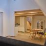Innenansicht eines modernen Wohnraums mit Holztreppe, Esstisch und K&uuml;chenbereich.