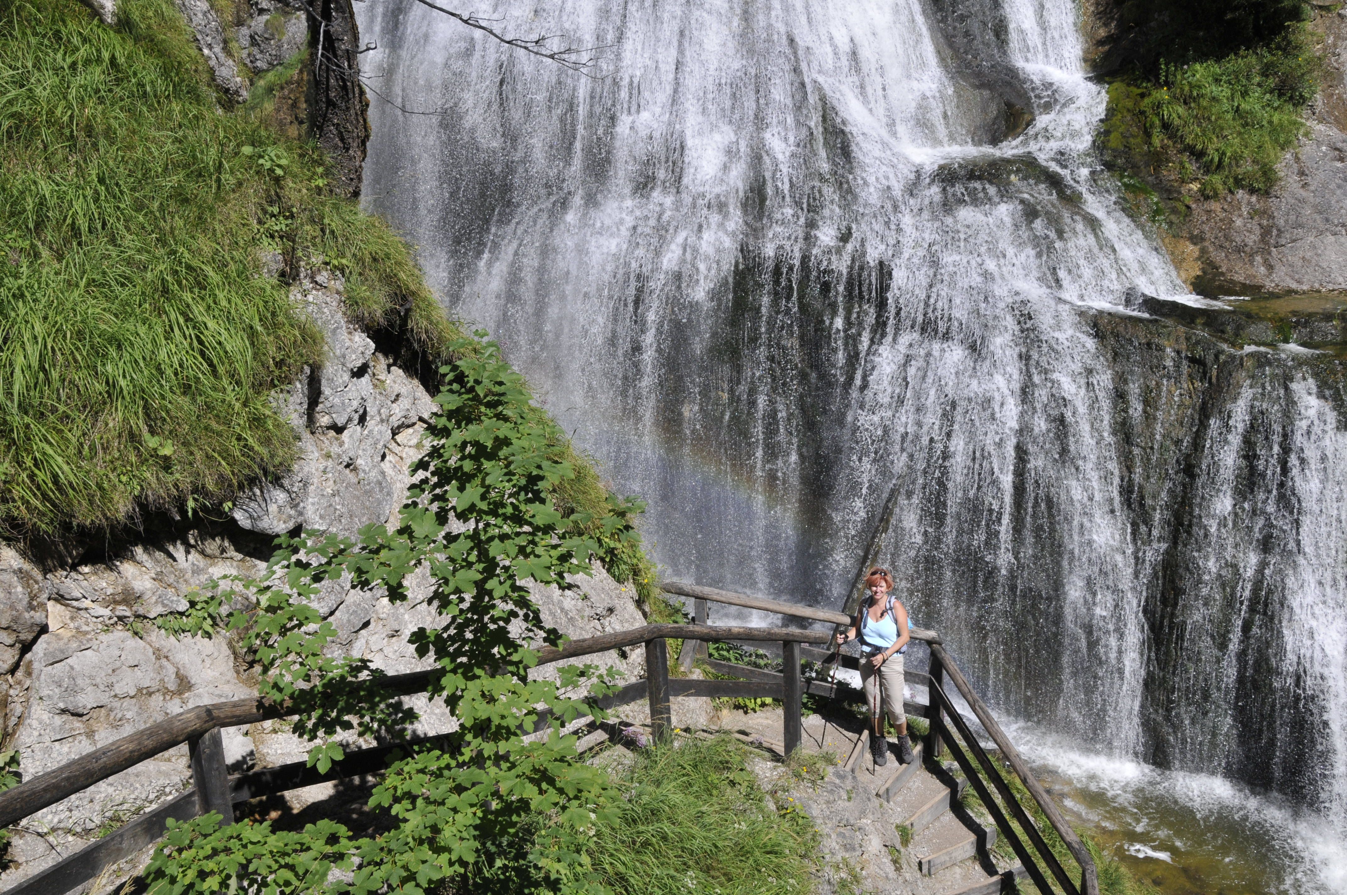 Eine Frau steht auf einer Treppe vor einem Wasserfall in der Wasserlochklamm Palfau.