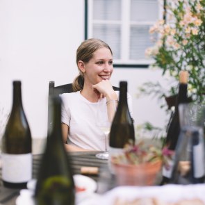 Winzerin Sophie Fidesser sitzt an einem mit Weinflaschen gefüllten Tisch 