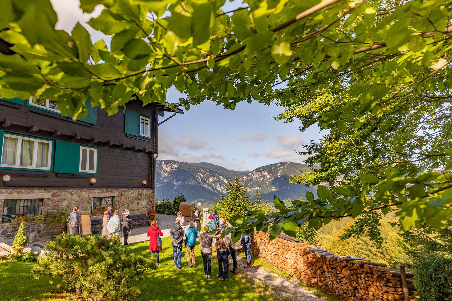 Gruppe von Menschen vor dem Looshaus am Kreuzberg mit Berglandschaft im Hintergrund.