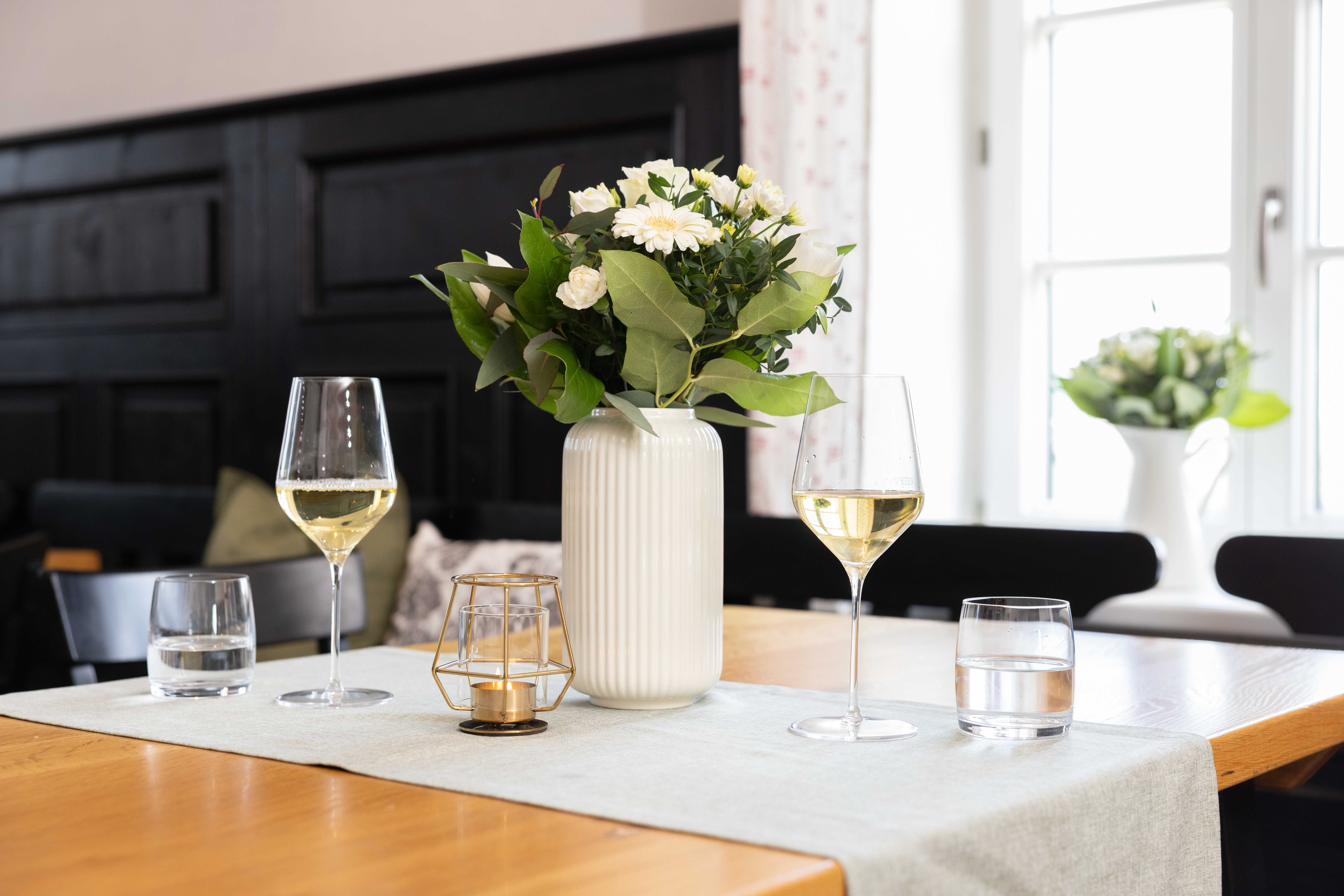 Tisch mit zwei Weingläsern, Vase und Kerze