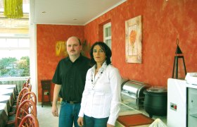 Zwei Personen stehen in einem Restaurant mit orange gestrichenen Wänden.