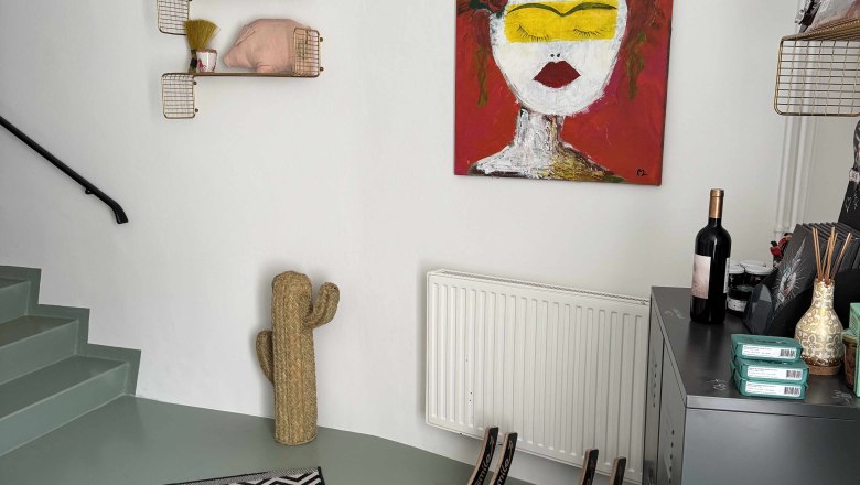 Eingangsbereich mit Kunstwerk, Kaktus-Dekoration und gestreiftem Teppich.