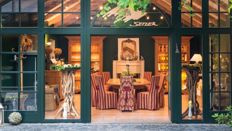 Ein eleganter Verkostungsraum mit Holzm&ouml;beln, gestreiften St&uuml;hlen und dekorativen Elementen. Der Raum ist durch gro&szlig;e Fenster sichtbar.