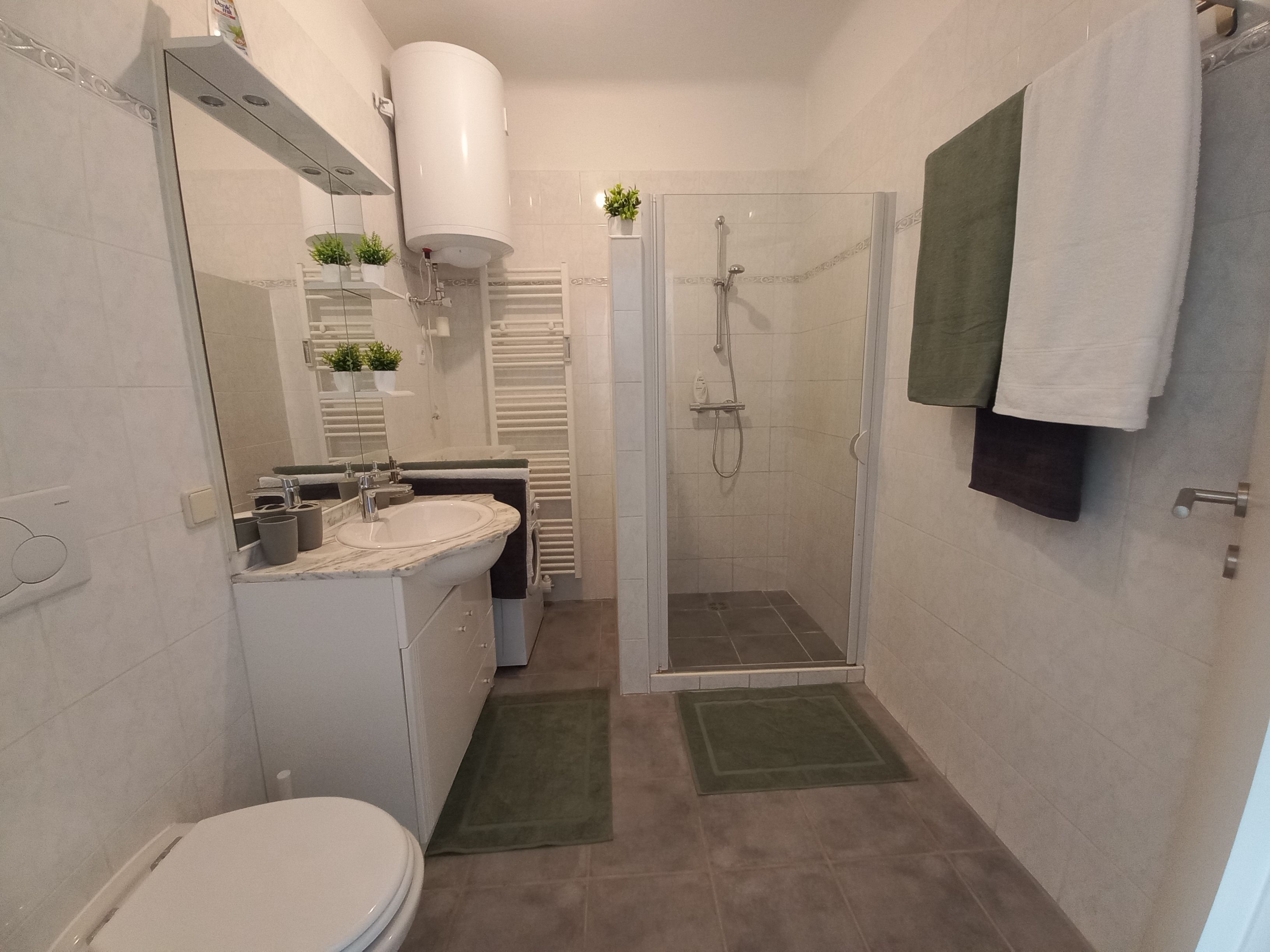 Modernes Badezimmer mit Dusche, Waschbecken, Spiegel und Handtüchern.