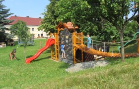 Spielplatz mit Klettergerüst, Rutsche und zwei Kindern beim Spielen.