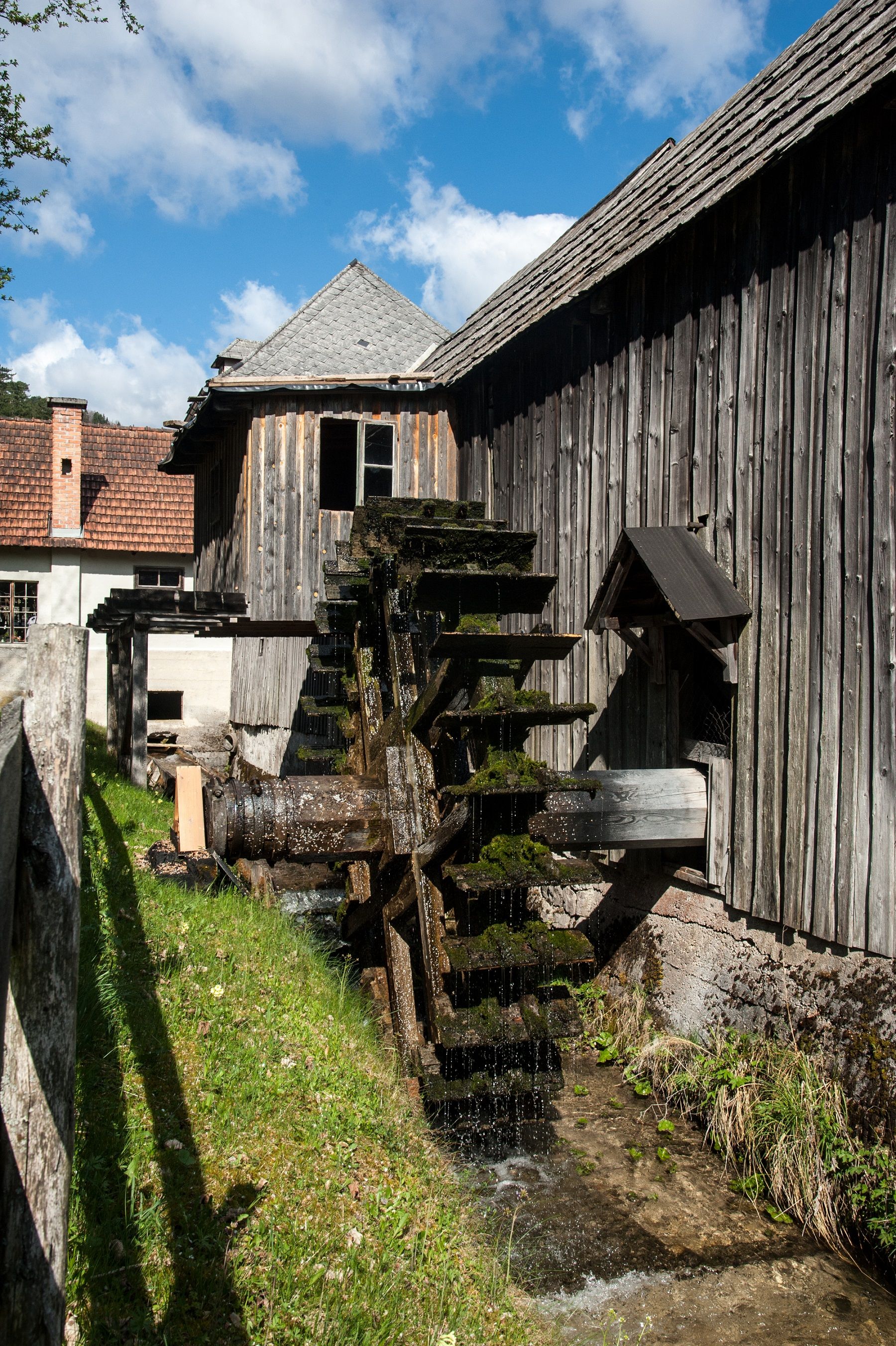 Ein altes Wasserrad an einem Holzgebäude im Freilichtmuseum bei sonnigem Wetter.