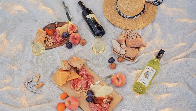 Picknick mit Wein, K&auml;se, Brot und Fr&uuml;chten auf einer Decke.