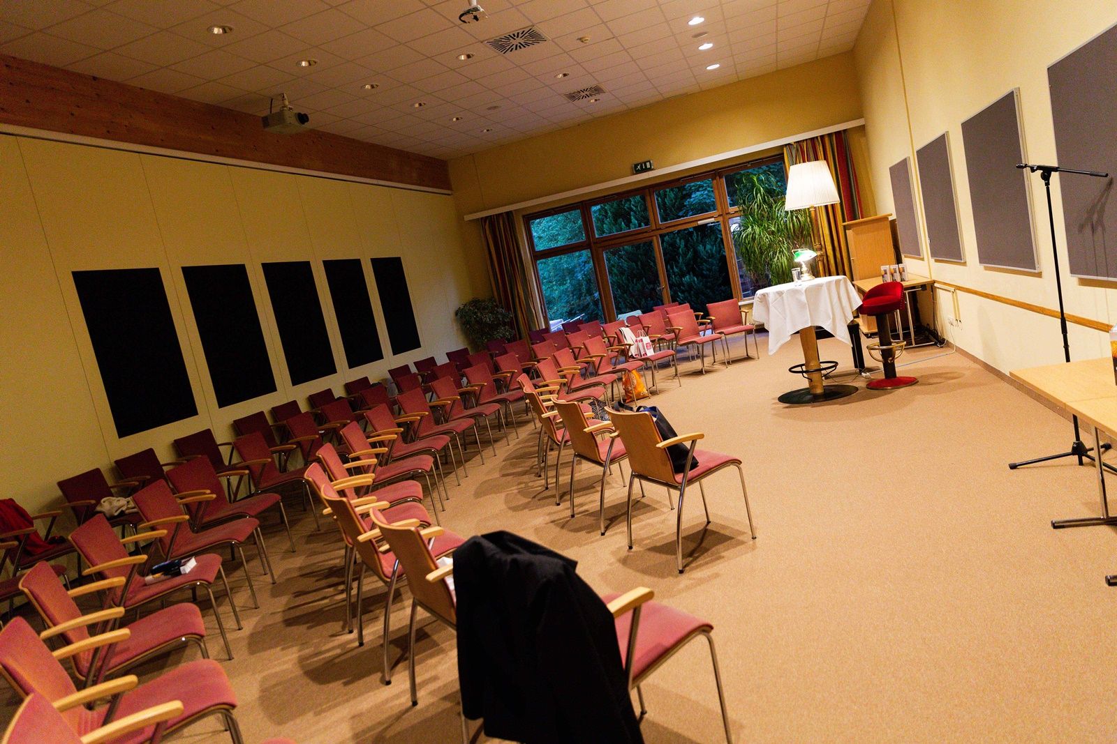 Leerer Veranstaltungsraum mit Stuhlreihen und Tisch mit Tischdecke.