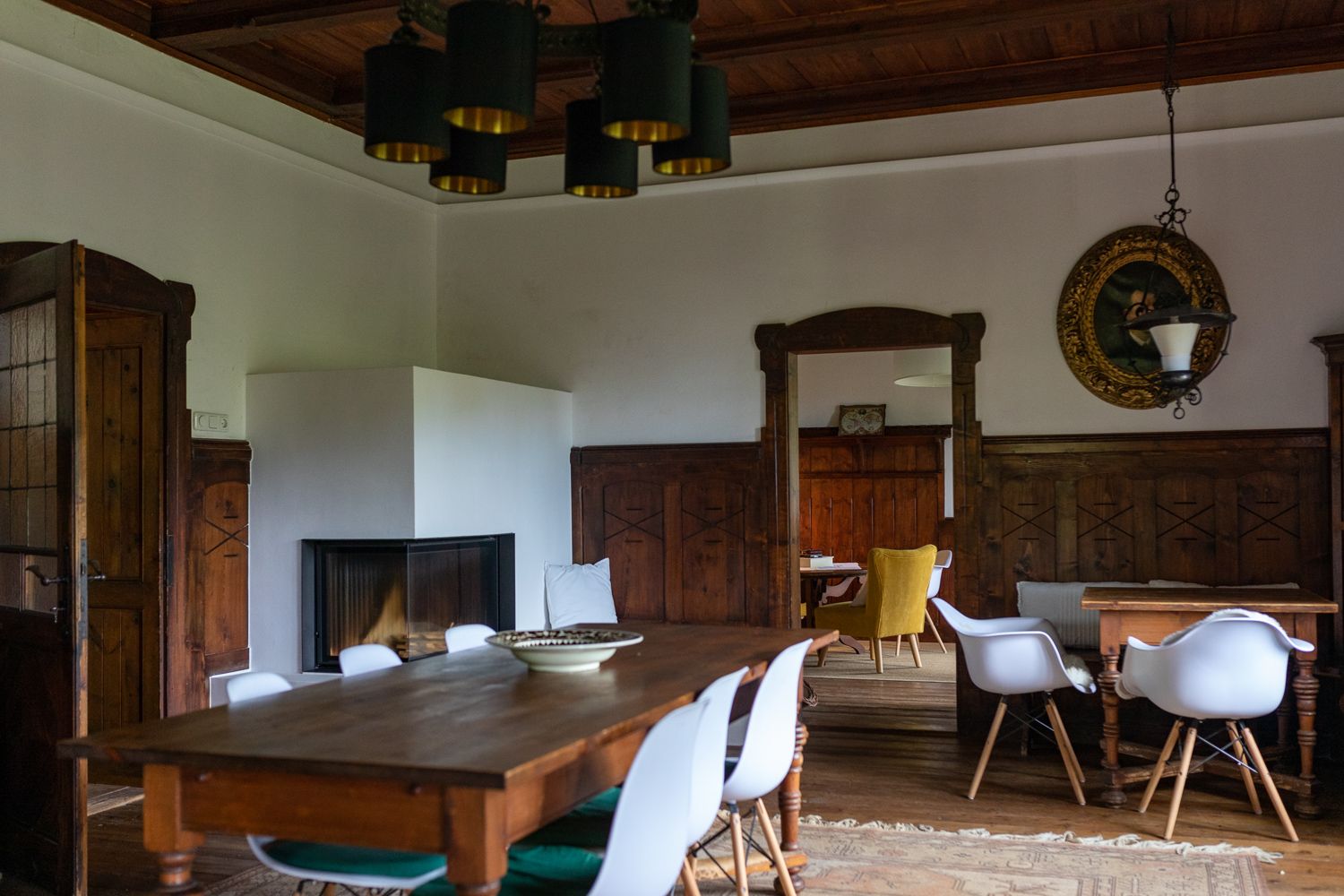 Esszimmer mit Holztisch, weißen Stühlen und Kamin.