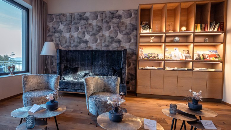 Gemütlicher Hotel-Loungebereich mit Sesseln, Couchtischen und Bücherregal.