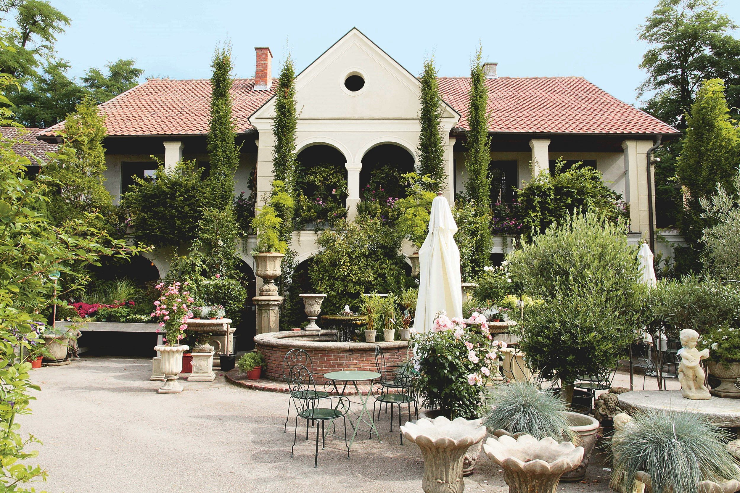 Ein gepflegter Garten mit einem eleganten Gebäude im Hintergrund, umgeben von Pflanzen und Blumen.