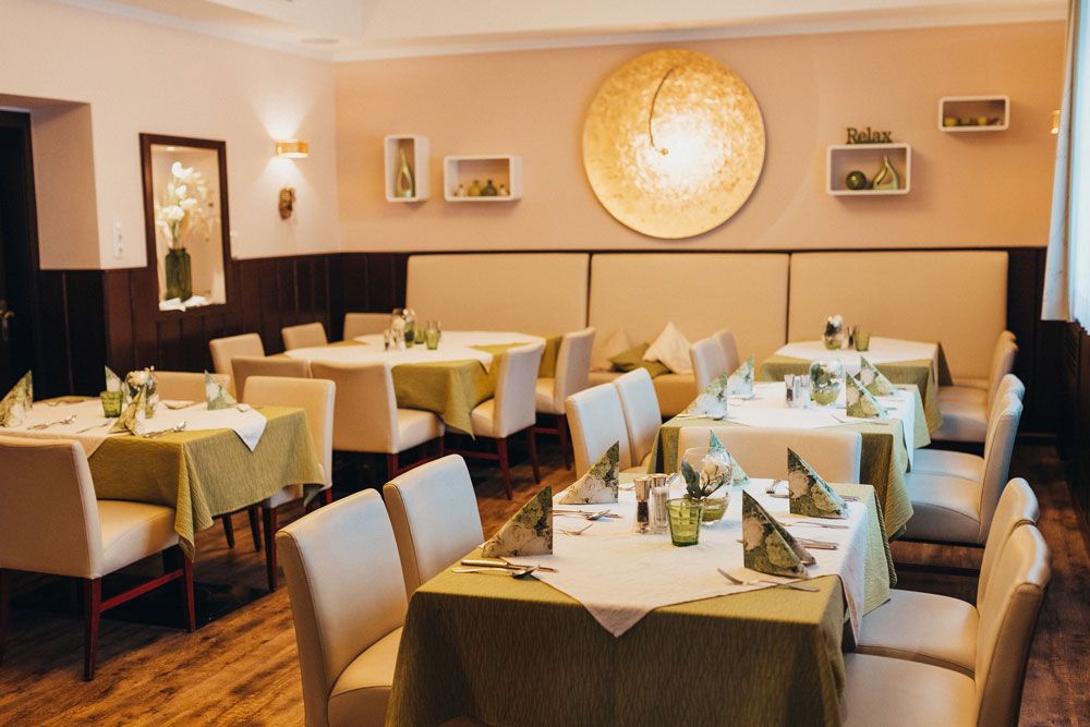 Elegantes Restaurant mit gedeckten Tischen und grünen Tischdecken.