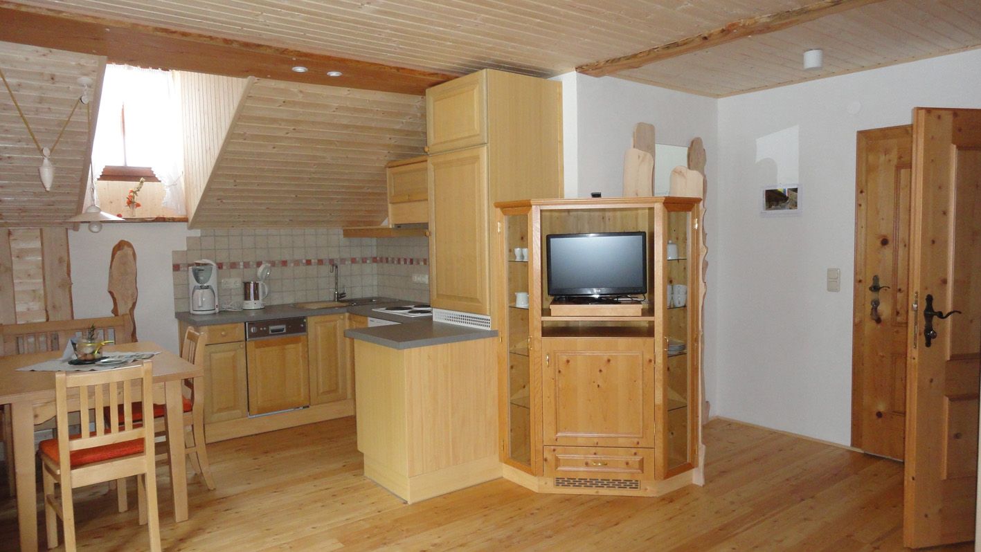 Gemütliche Dachgeschosswohnung mit Holzmöbeln, Küchenzeile und Esstisch.