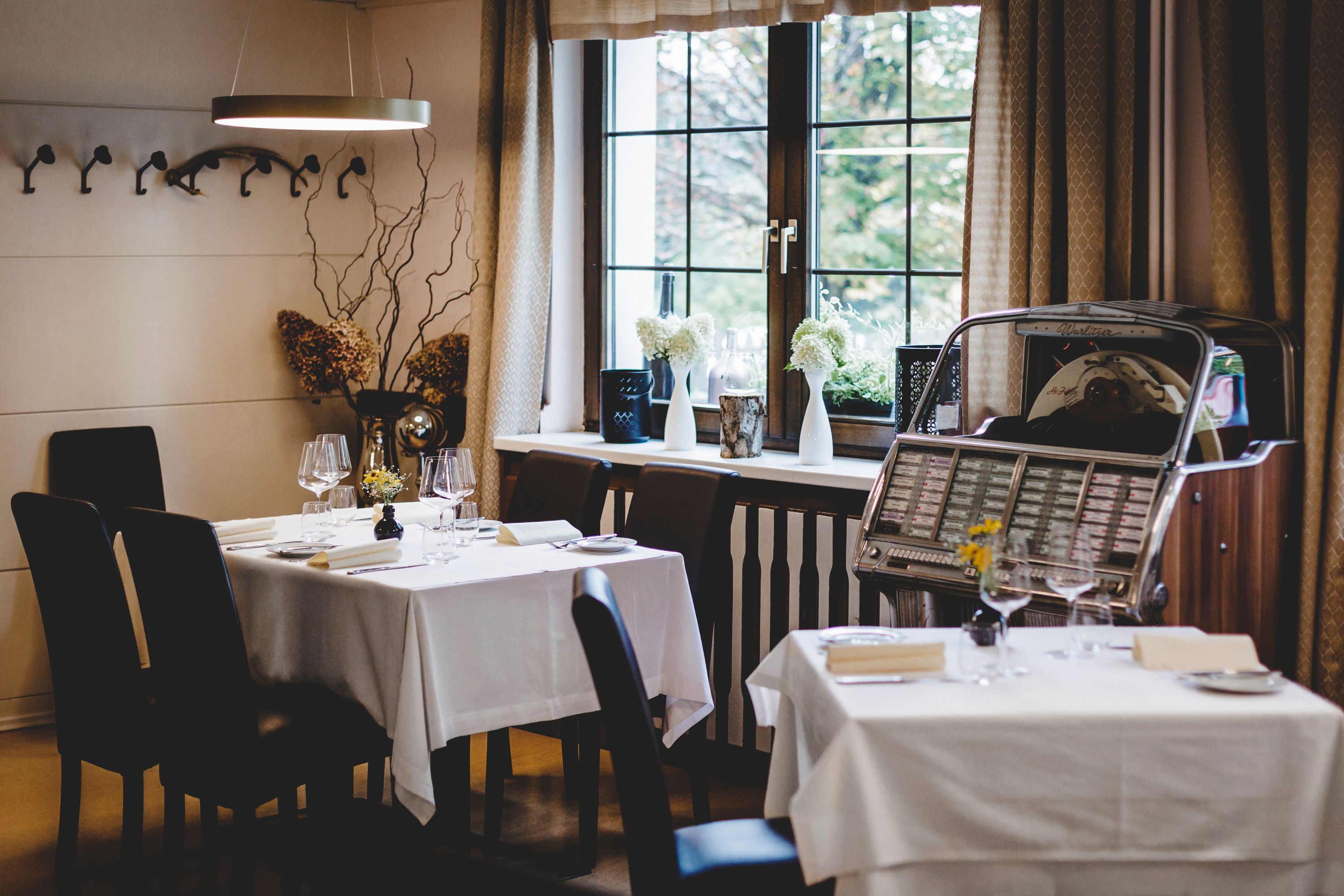 Gemütliches Restaurant mit gedeckten Tischen und Jukebox am Fenster.