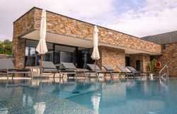 Außenansicht eines modernen Hotels mit Pool und Liegestühlen.