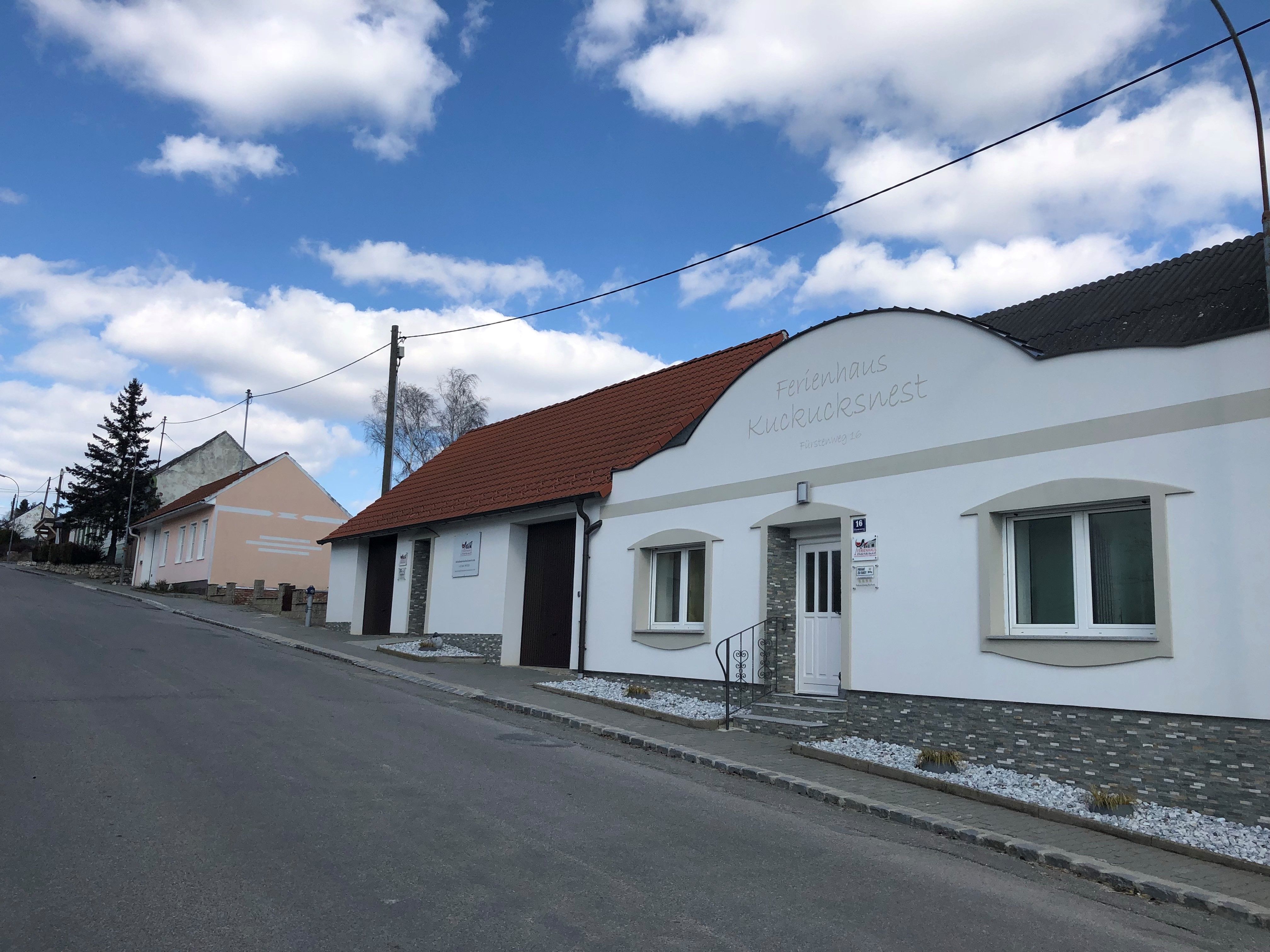 Straße mit Ferienhaus Kuckucksnest und blauen Himmel.