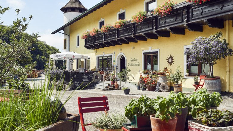 Gemütliches Gasthaus mit Blumenschmuck und Terrasse, ländliche Atmosphäre.