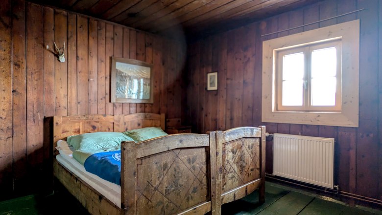 Rustikales Doppelzimmer mit Holzwänden und -möbeln, zwei Einzelbetten, Fenster und Heizung.