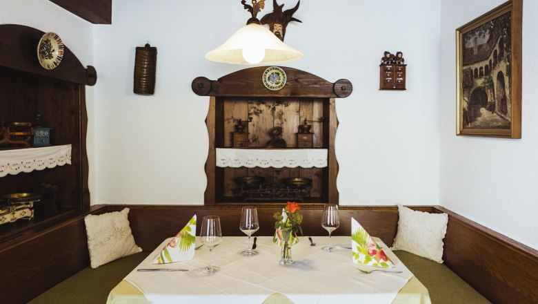 Gem&uuml;tliche Sitzecke in einem Restaurant mit Holzm&ouml;beln, dekorativen Details und gedecktem Tisch.