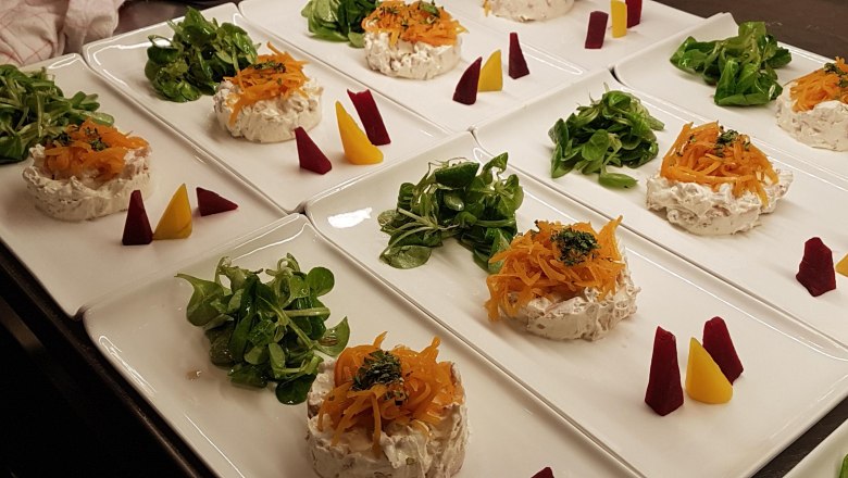 Vorspeisenteller mit Salat, Frischk&auml;se und Gem&uuml;se auf wei&szlig;en Tellern.