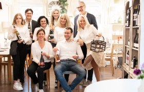 Gruppe von Menschen in einem Raum mit Weinflaschen.