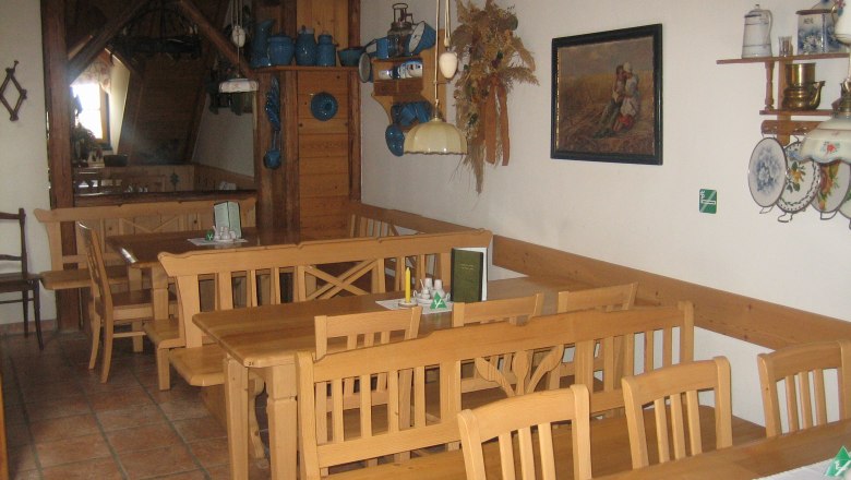 Innenansicht eines traditionellen Gastraums mit Holzm&ouml;beln und rustikaler Dekoration.