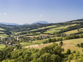 Panoramablick auf die h&uuml;gelige Landschaft um Krumbach mit Feldern, W&auml;ldern und Schneeberg im Hintergrund