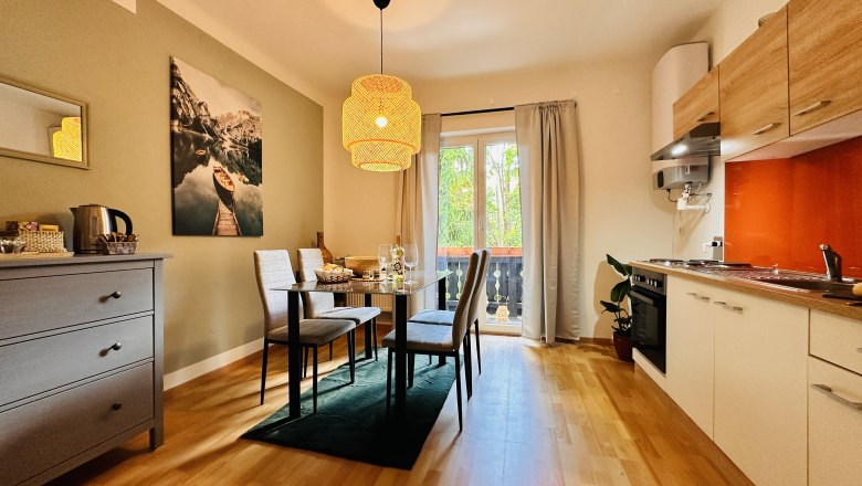 Gemütliches Apartment mit Esstisch, Stühlen, Küchenzeile und Balkon.