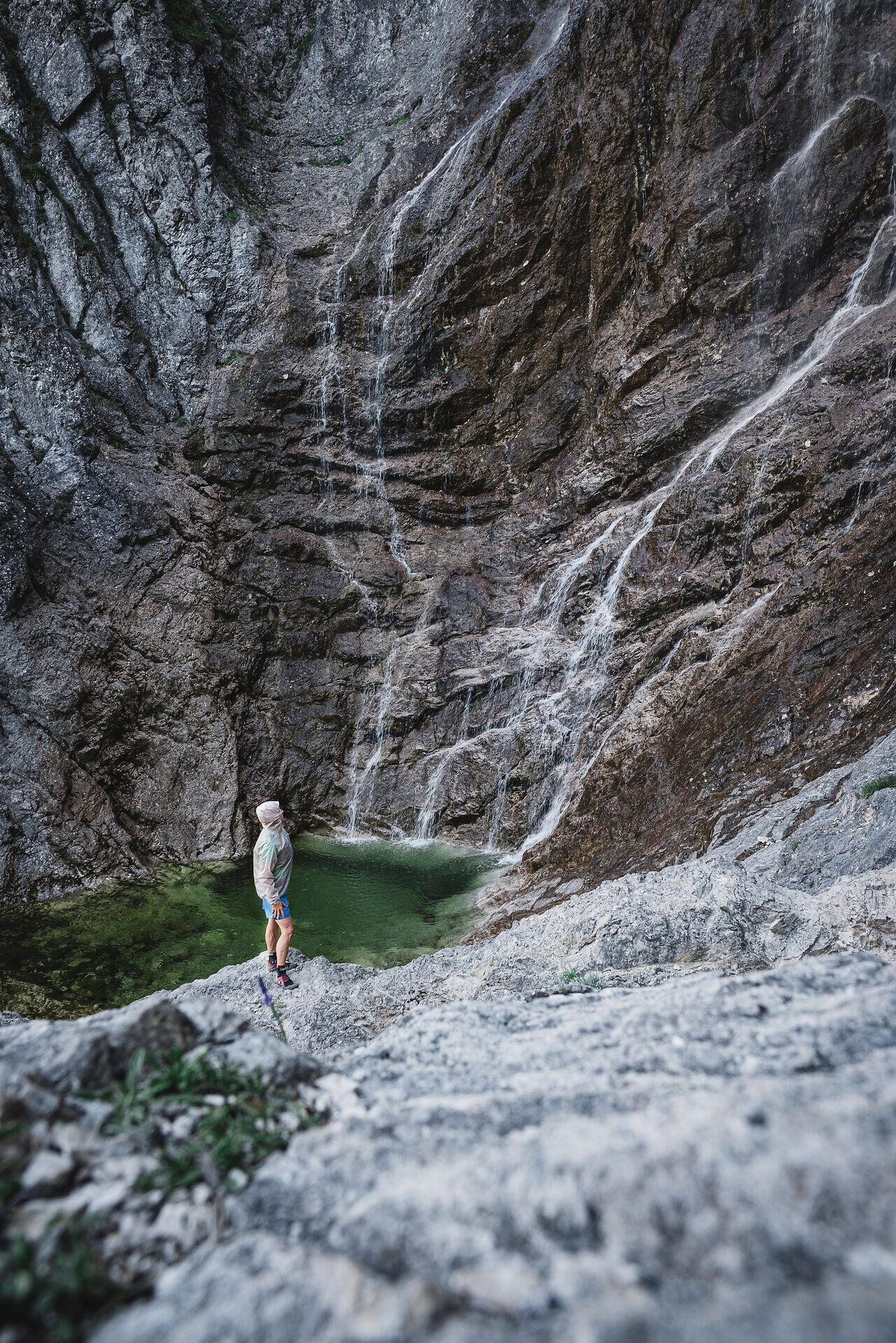 Ein Trailrunner steht am Rand eines beeindruckenden Wasserfalls, umgeben von majestätischen Felsen und üppigem Grün. Das glitzernde Wasser stürzt in ein klares, smaragdgrünes Becken und schafft eine Atmosphäre der Ruhe und Erfrischung. Hier in den Ötschergräben wird der Sommer in den Bergen zum unvergesslichen Erlebnis.