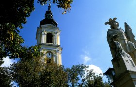 Turm der Pfarrkirche Großweikersdorf mit Statue im Vordergrund.