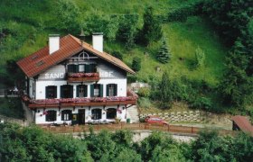 Traditionelles Haus namens Sand-Hof in grüner Landschaft.