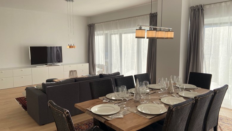 Moderner Wohn-Essbereich mit Esstisch, St&uuml;hlen, Sofa und Fernseher.