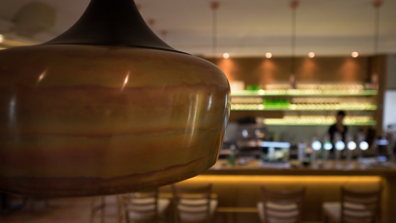 Nahaufnahme einer Lampe in einem stilvollen Caf&eacute; mit Bar im Hintergrund.