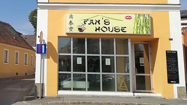 Außenansicht eines Restaurants namens Fan's House mit gelber Fassade und großen Fenstern.