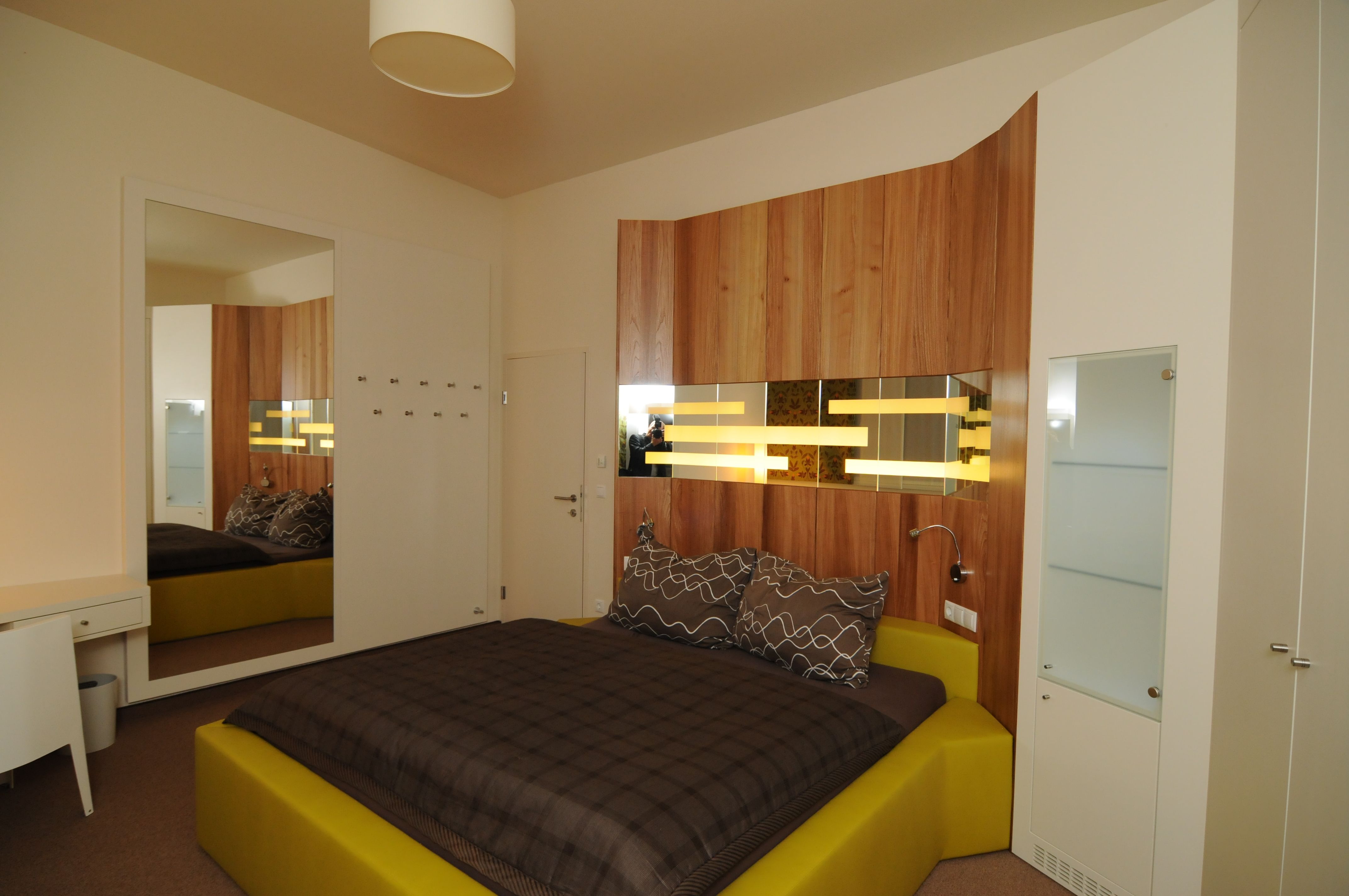 Modernes Schlafzimmer mit Holzverkleidung und gelbem Bett.