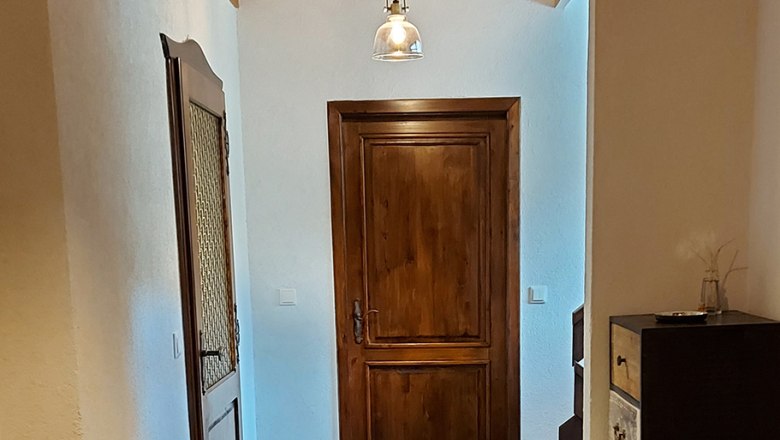 Ein Flur mit Holzt&uuml;ren, Holzdecke und modernen Lampen.