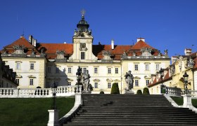 Frontansicht des Schlosses Valtice mit Treppen und Statuen im Vordergrund.