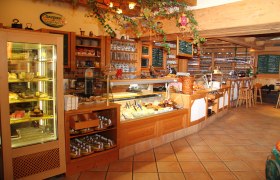 Innenansicht eines gemütlichen Cafés mit Theke und Auslagen.