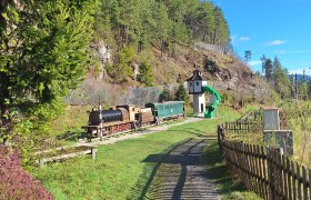 Kinderspielplatz mit einer Holzlokomotive und einem Rutschenturm.